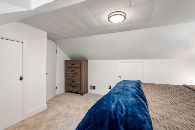 bedroom featuring visible vents, vaulted ceiling, light carpet, and baseboards