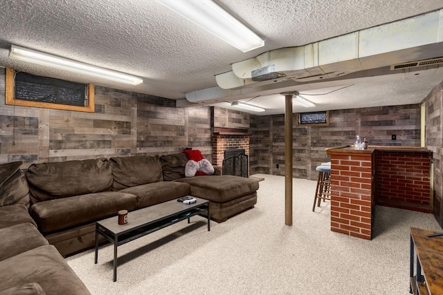 carpeted living room featuring wooden walls, visible vents, a fireplace, and a textured ceiling