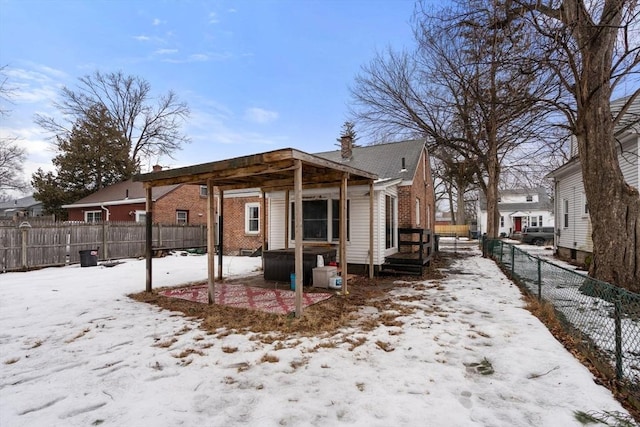 snow covered house featuring a fenced backyard and brick siding