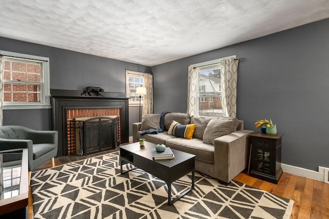 living area featuring visible vents, baseboards, wood finished floors, a textured ceiling, and a fireplace