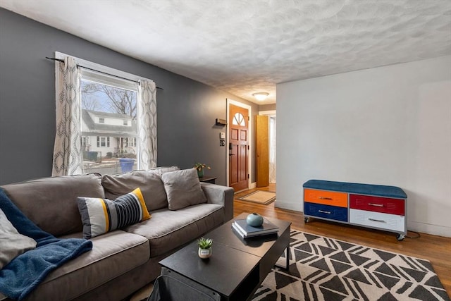 living room with a textured ceiling, baseboards, and wood finished floors