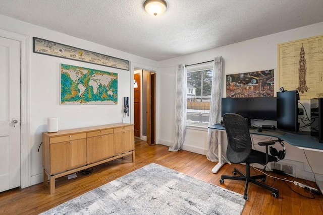 home office featuring a textured ceiling, wood-type flooring, and baseboards