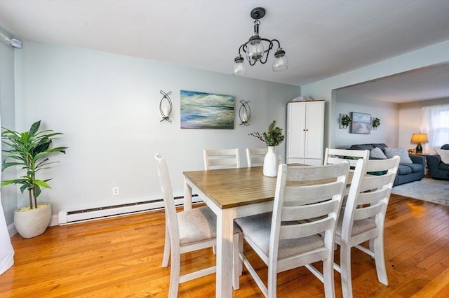 dining space featuring hardwood / wood-style flooring, a baseboard radiator, and an inviting chandelier