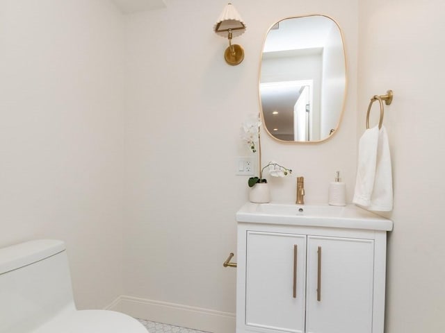 half bath featuring toilet, vanity, and baseboards