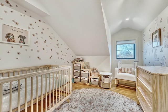 bedroom featuring wallpapered walls, light wood-style floors, and vaulted ceiling