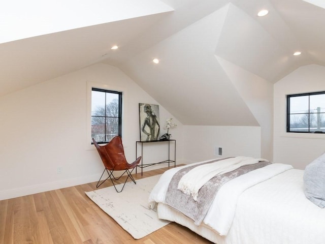 bedroom with vaulted ceiling, multiple windows, light wood-style floors, and visible vents