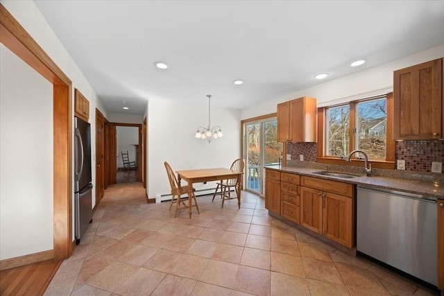 kitchen with a baseboard heating unit, stainless steel appliances, a sink, backsplash, and pendant lighting