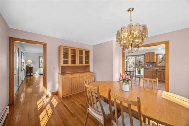 dining area featuring light wood-type flooring, an inviting chandelier, a baseboard radiator, and baseboards