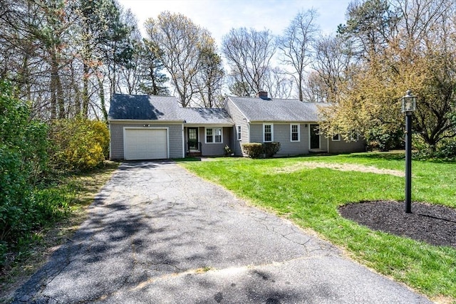 ranch-style home featuring an attached garage, a chimney, driveway, and a front lawn