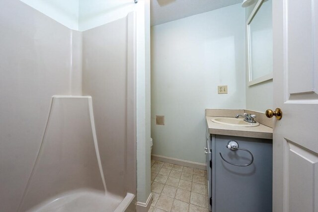 bathroom featuring vanity, baseboards, toilet, and a shower stall