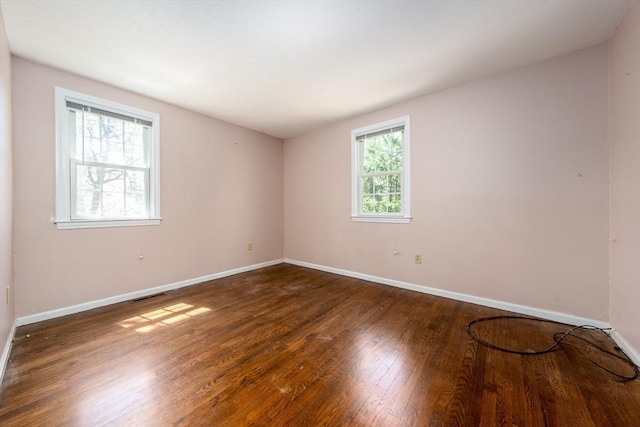 unfurnished room with wood-type flooring, baseboards, and visible vents