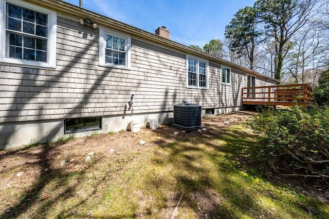 view of property exterior featuring central AC, a chimney, and a wooden deck