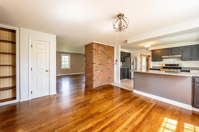 kitchen featuring backsplash, range, wood finished floors, stainless steel fridge with ice dispenser, and under cabinet range hood