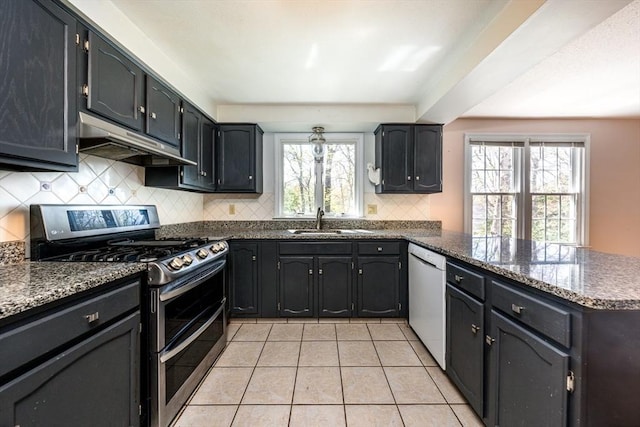 kitchen with a peninsula, white dishwasher, under cabinet range hood, range with two ovens, and a sink