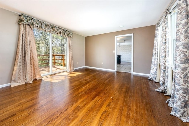 spare room with baseboards and wood finished floors