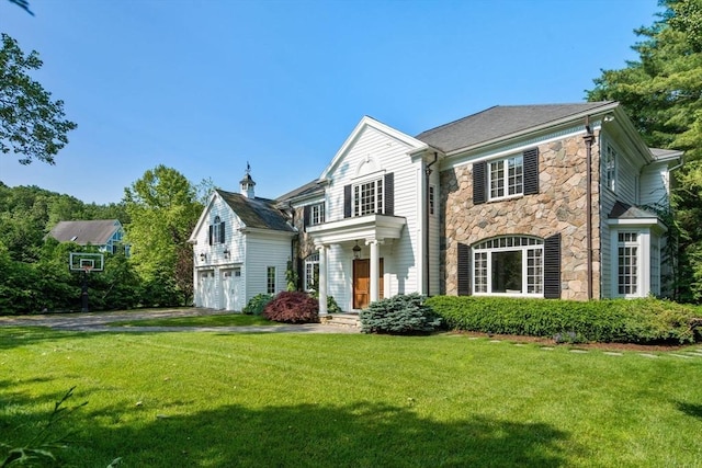 69 Princeton Rd, Brookline, MA 02467 - view of front facade with stone siding, an attached garage, a front lawn, and driveway