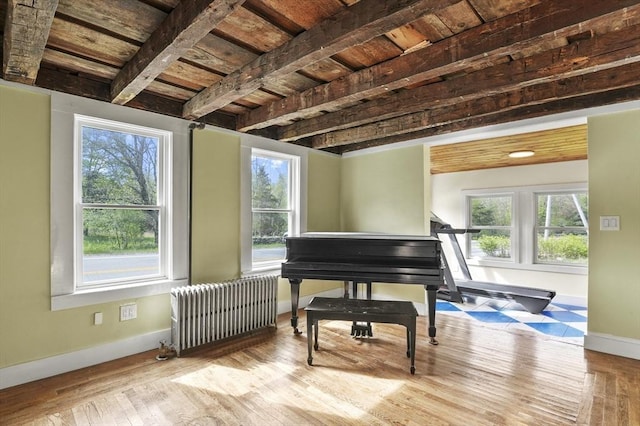 living area with radiator heating unit, baseboards, hardwood / wood-style flooring, healthy amount of natural light, and wooden ceiling