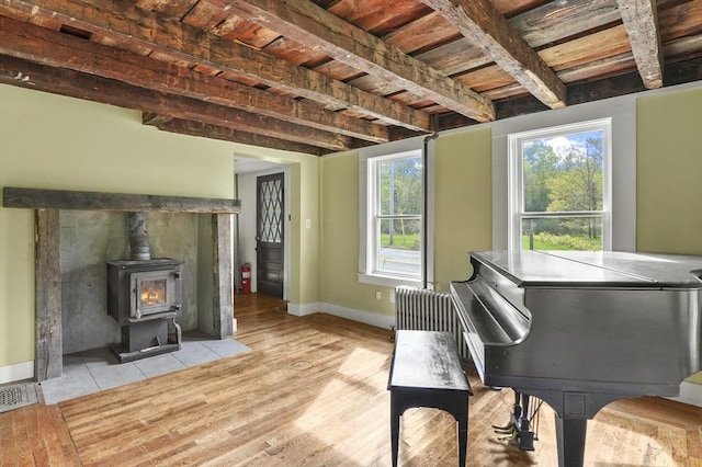 living area featuring light wood-type flooring, baseboards, a wood stove, and radiator heating unit