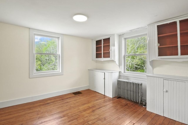 unfurnished room featuring radiator heating unit, light wood-style floors, and baseboards