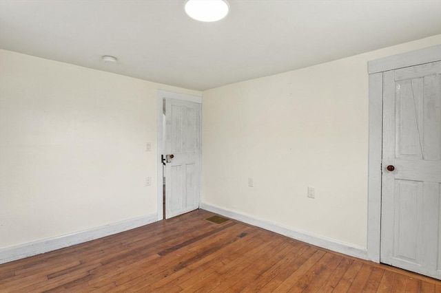 empty room featuring baseboards, hardwood / wood-style flooring, and a smoke detector