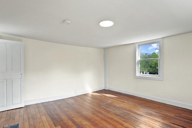 spare room featuring wood-type flooring, a smoke detector, and baseboards