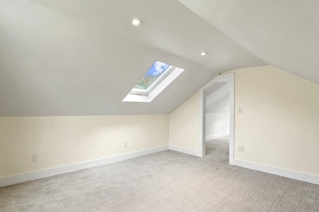 additional living space with a skylight, vaulted ceiling, light carpet, recessed lighting, and baseboards