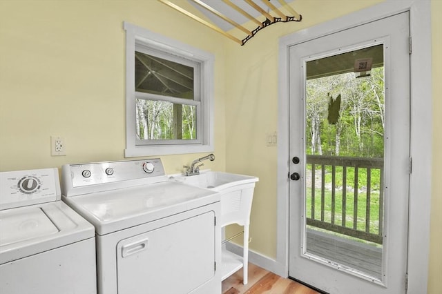 laundry area featuring washer and clothes dryer, light wood finished floors, and baseboards