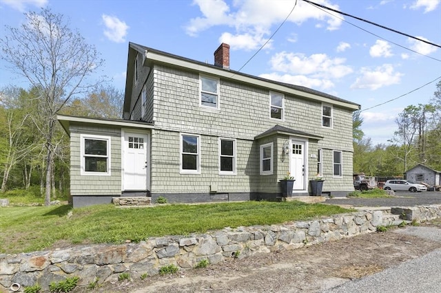 rear view of house featuring a chimney and a yard