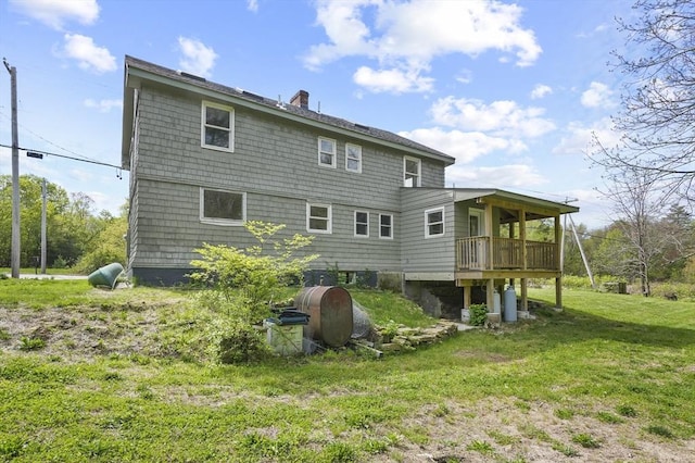 back of property with a yard, a chimney, and a wooden deck