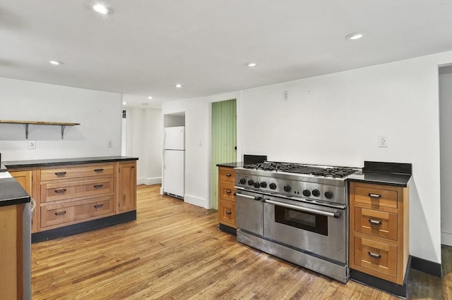 kitchen with range with two ovens, freestanding refrigerator, dark countertops, light wood-type flooring, and recessed lighting