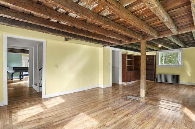unfurnished living room with radiator, hardwood / wood-style flooring, baseboards, beam ceiling, and wooden ceiling