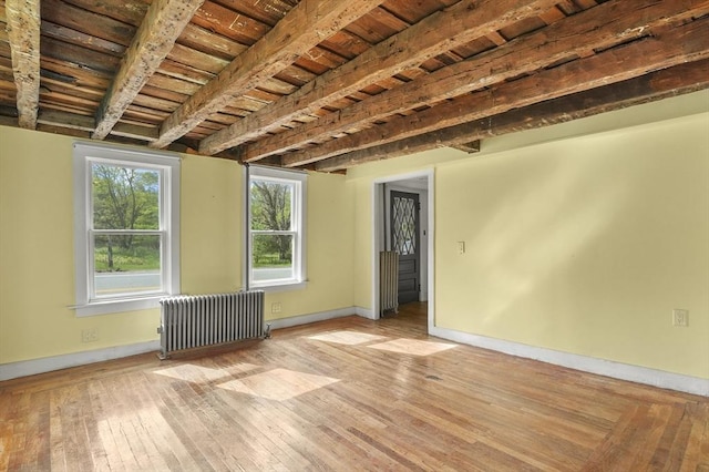 empty room featuring radiator heating unit, baseboards, wood ceiling, hardwood / wood-style flooring, and beam ceiling