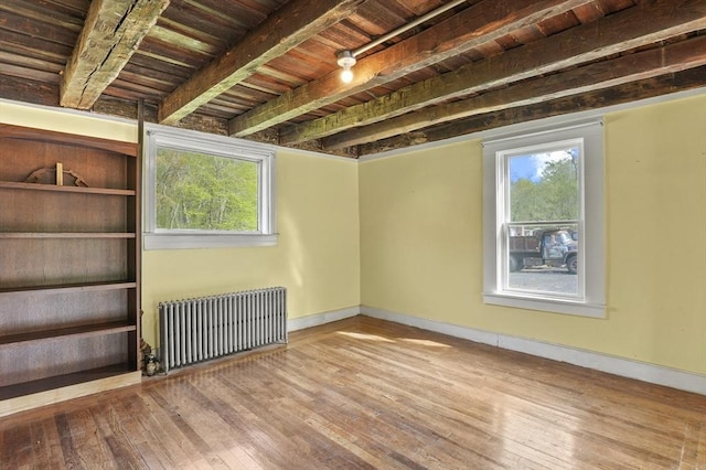 unfurnished room featuring radiator, hardwood / wood-style flooring, healthy amount of natural light, wood ceiling, and baseboards