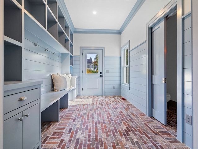 mudroom featuring crown molding and wood walls