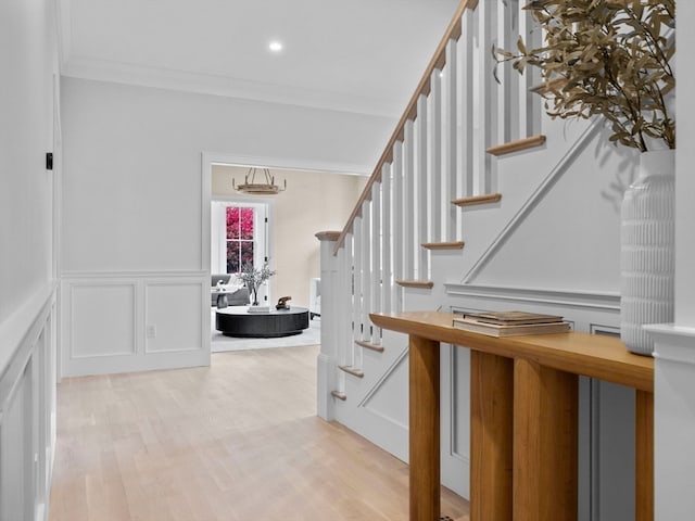 staircase with ornamental molding and hardwood / wood-style floors