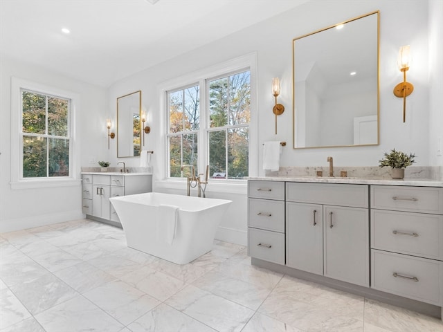 bathroom featuring a wealth of natural light, vanity, and a tub to relax in