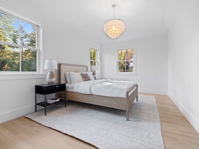 bedroom with light hardwood / wood-style flooring and an inviting chandelier