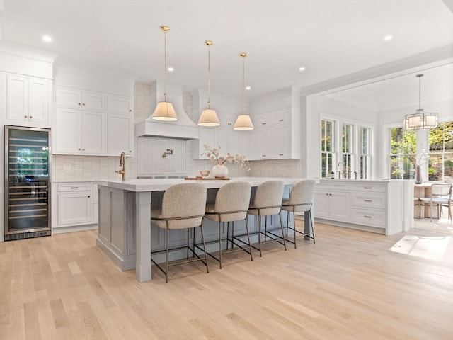 kitchen with a spacious island, white cabinets, beverage cooler, and pendant lighting