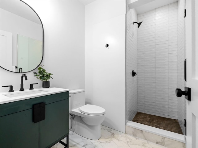 bathroom featuring vanity, a tile shower, and toilet