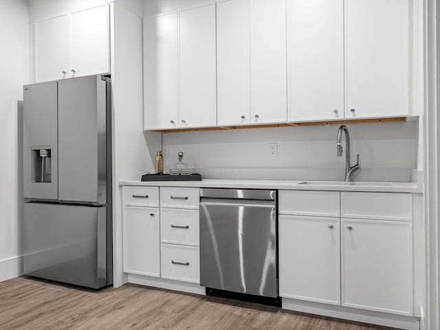 kitchen featuring white cabinetry, light hardwood / wood-style floors, stainless steel appliances, and sink