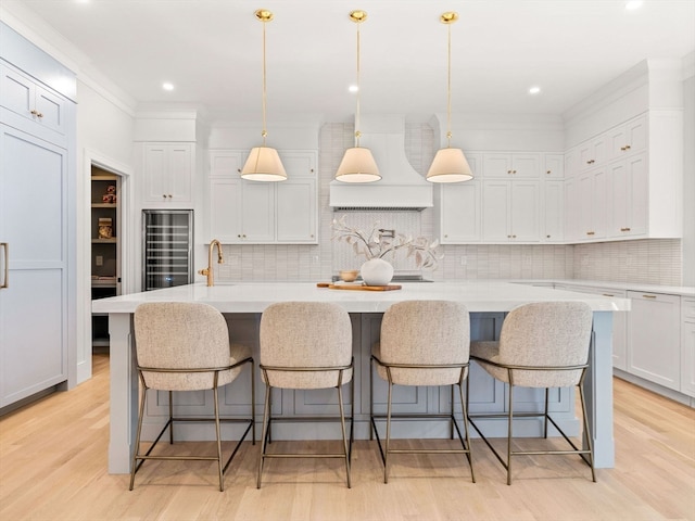 kitchen with hanging light fixtures, light wood-type flooring, and a large island with sink