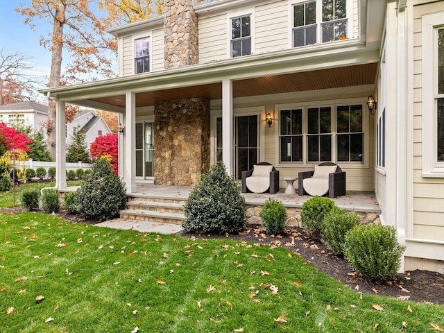 view of exterior entry with a porch and a lawn