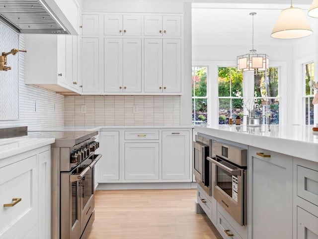 kitchen featuring pendant lighting, stainless steel appliances, wall chimney exhaust hood, and plenty of natural light