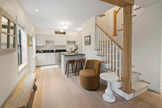 kitchen featuring white cabinetry, light wood-type flooring, sink, a breakfast bar area, and stainless steel dishwasher