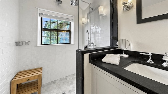 bathroom featuring tile walls, tiled shower, and vanity