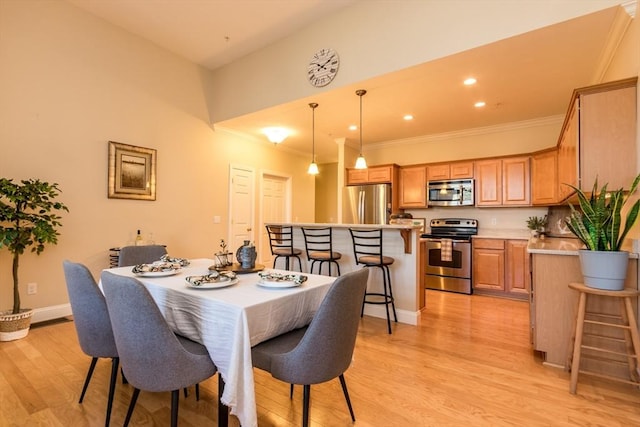 dining room with light wood-type flooring and crown molding