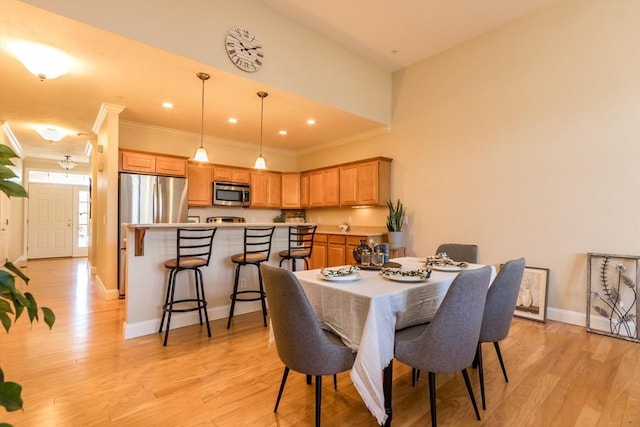 dining area with light wood-type flooring and ornamental molding