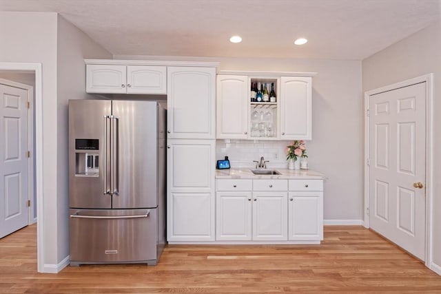 kitchen with tasteful backsplash, high end fridge, sink, and white cabinets