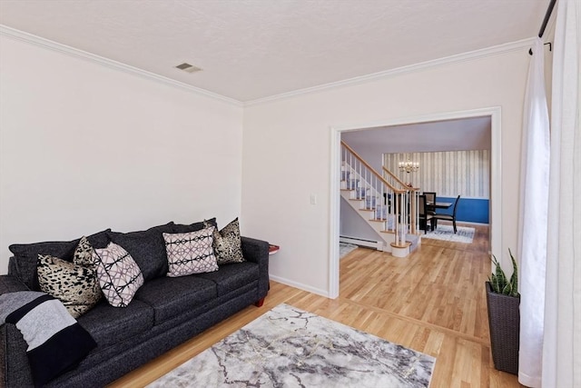 living room with a notable chandelier, crown molding, a baseboard radiator, and hardwood / wood-style floors