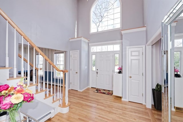 foyer entrance with a towering ceiling and light hardwood / wood-style flooring